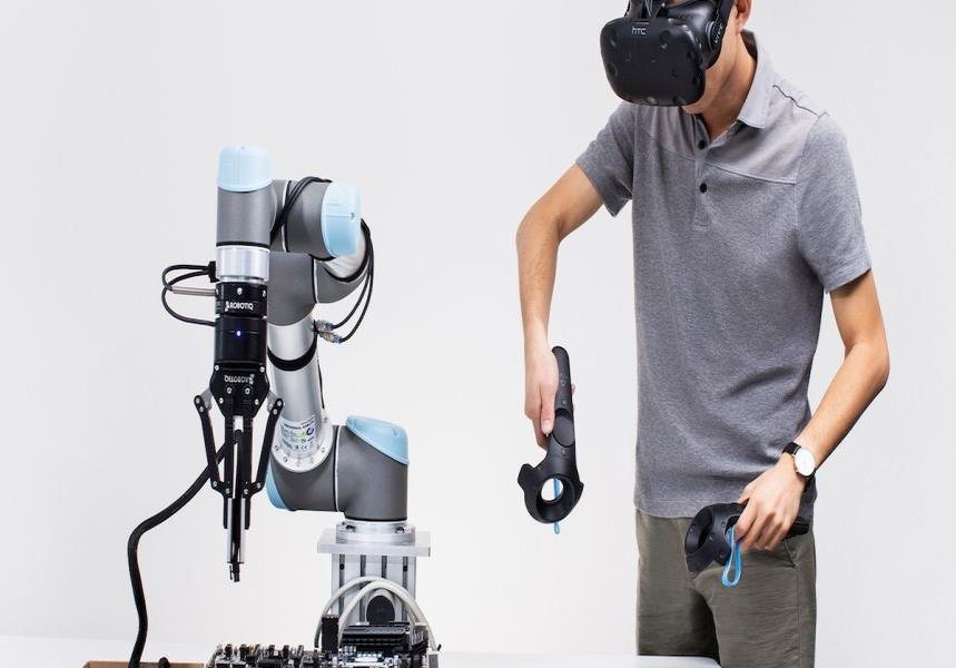 Operatore con controller VR accanto a un braccio robotico